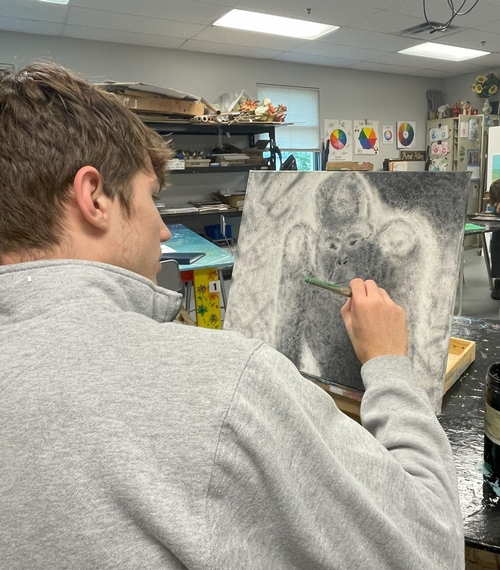 student drawing with charcoal in middle school arts class