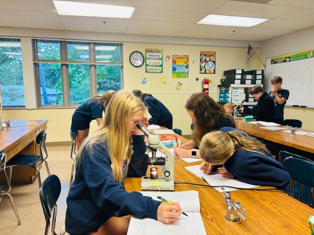 Saint Francis Middle School student using microscope in class